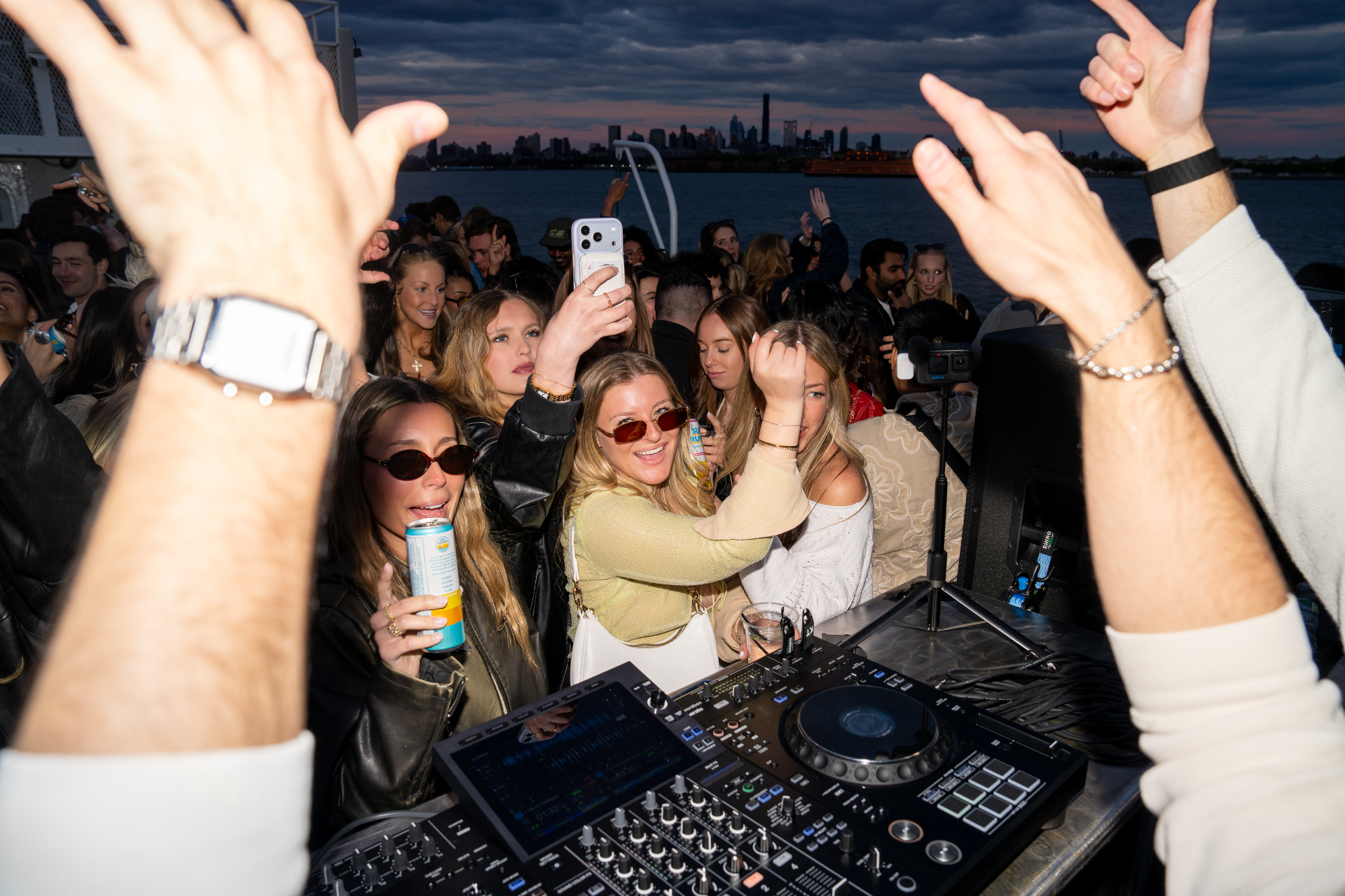 Guest laughing on a New York Booze Cruise at sunset with the Statue of Liberty behind